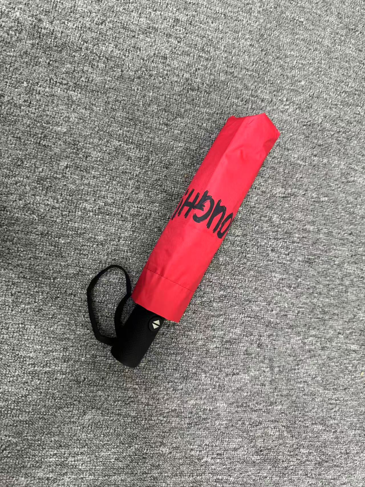 Red umbrella with 'ENOUGH!' text on a neutral background. UV coated for sun protection.