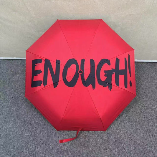 Red umbrella with 'ENOUGH!' text on a neutral background. UV coated for sun protection. 