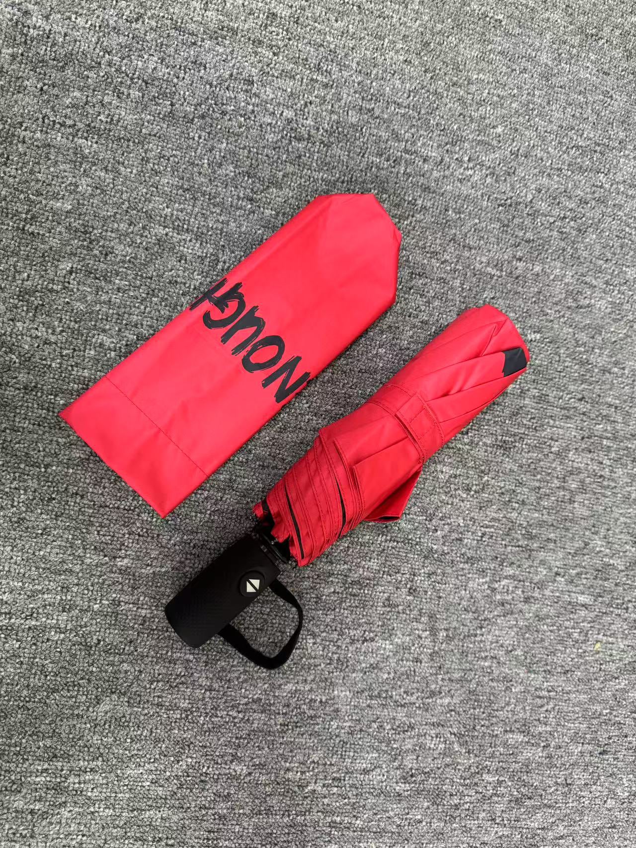Red umbrella with 'ENOUGH!' text on a neutral background. UV coated for sun protection. 