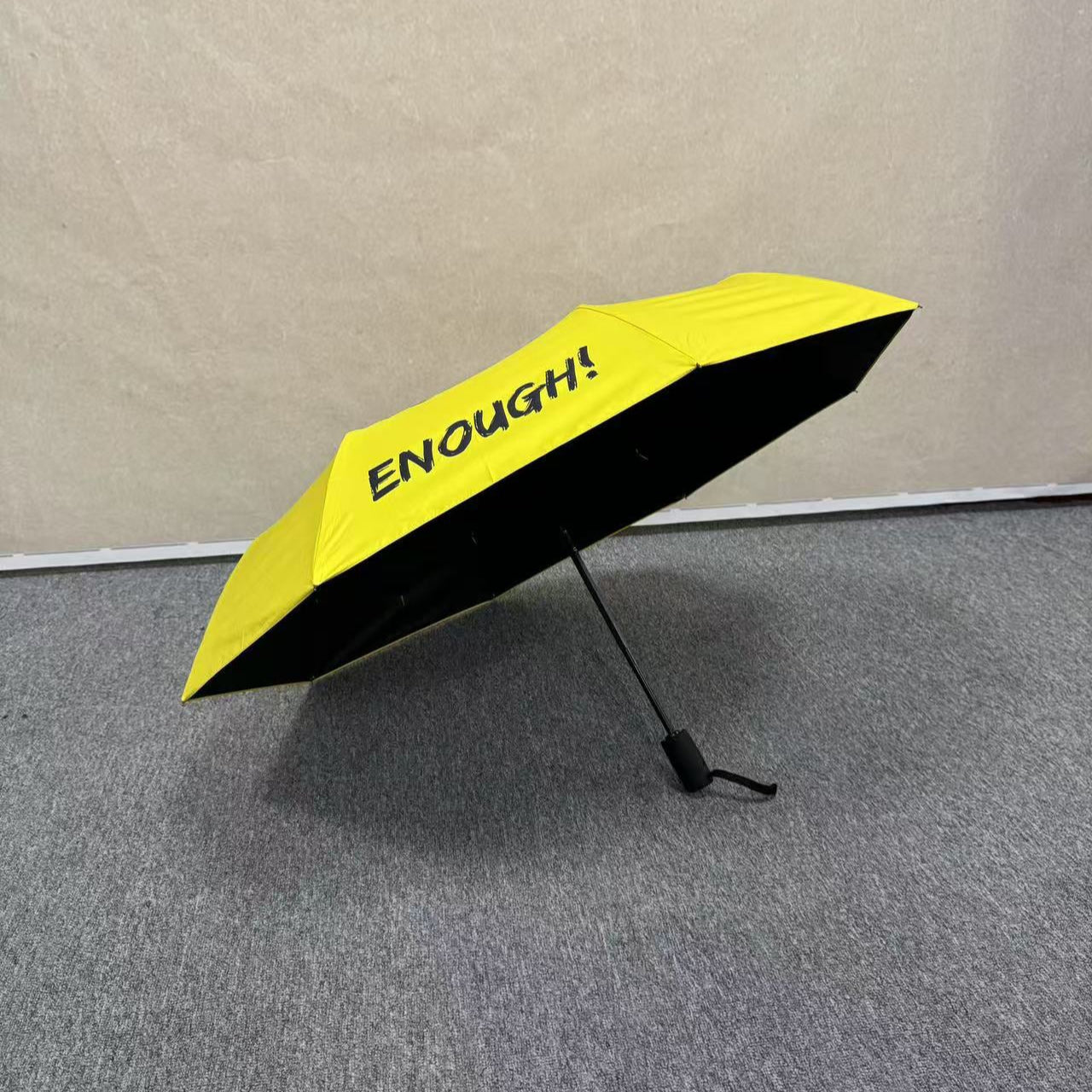 No Kings.  Bright yellow protest umbrella  with a picture of a black crown with a red X painted over the crown.